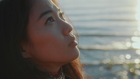 close-up of contemplative asian woman standing on lake shore