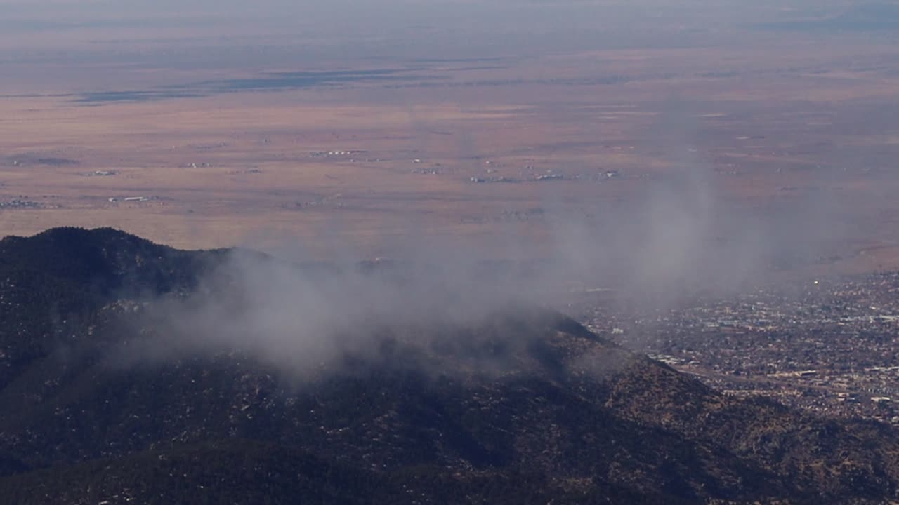 albuquerque visible en la distancia mientras los terrones se desplazan suavemente por las cimas de las montañas sandia