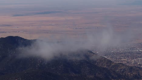 Albuquerque-Ist-In-Der-Ferne-Sichtbar,-Während-Erdklumpen-Sanft-über-Die-Gipfel-Der-Sandia-Berge-Treiben