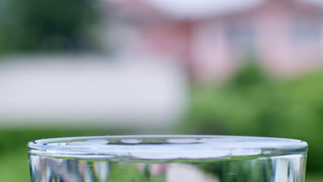 droplets of water are formed as the water lands into a glass filled with clean, clear water