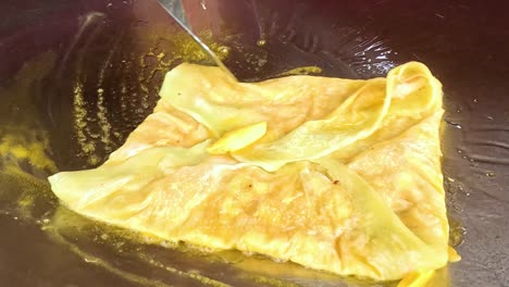 a close-up view of a roti being flipped and cooked to golden perfection on a hot griddle.
