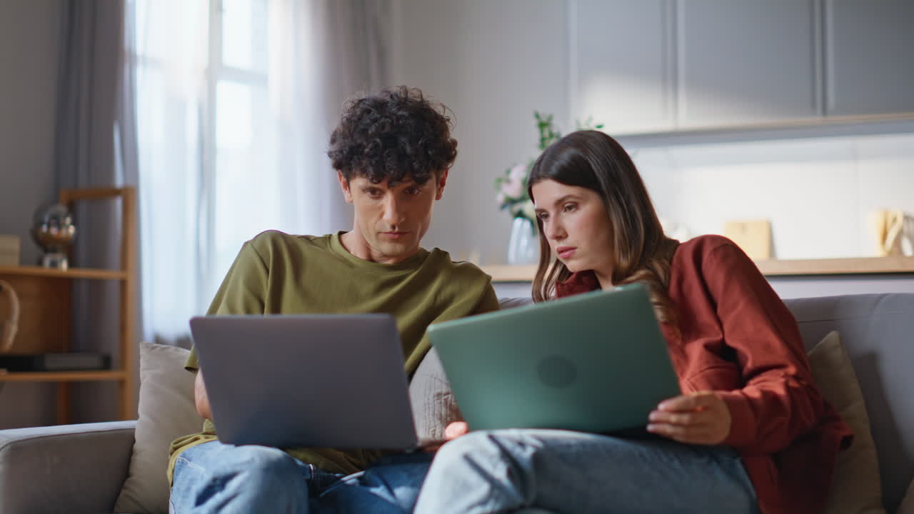 Serious lovers discussing computer screen talking together at couch closeup