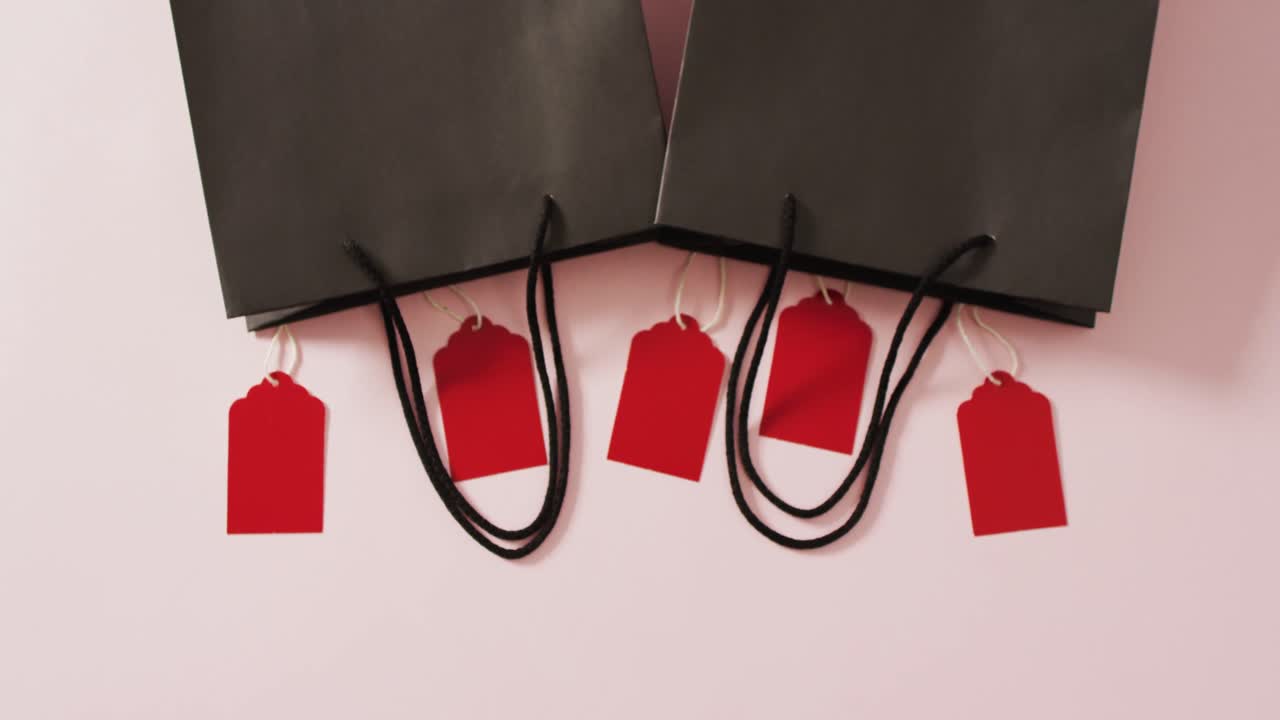 두 개의 검은색 선물 봉투와 5 개의 빨간색 판매 태그가  ⁇ 색 배경에 복사 공간으로