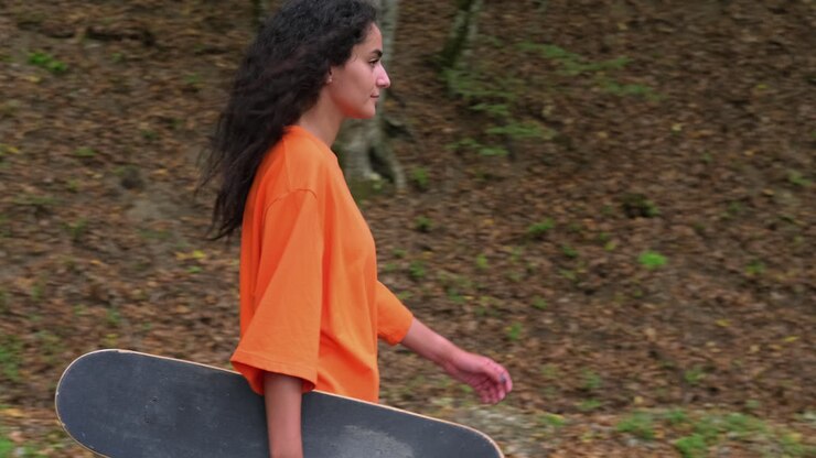 Adolescente con uno skateboard in un bosco autunnale