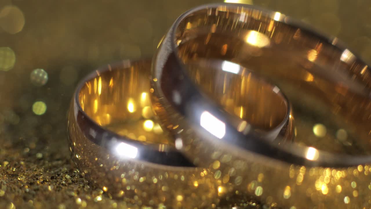 Wedding gols rings lying on shiny glossy surface. Shining with light. Close-up