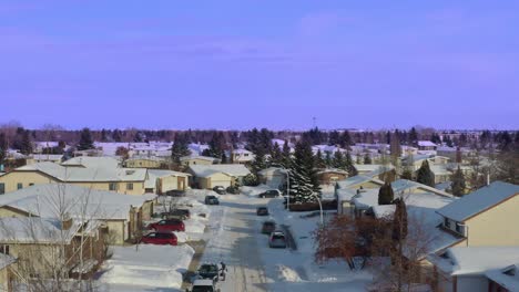 arial panout over blue sky snow covered cars vans streets sidewalks at sidestreet of an edmonton alberta subarb of middle to upper class closeup of low rised dettached homes that are paid off mortgage