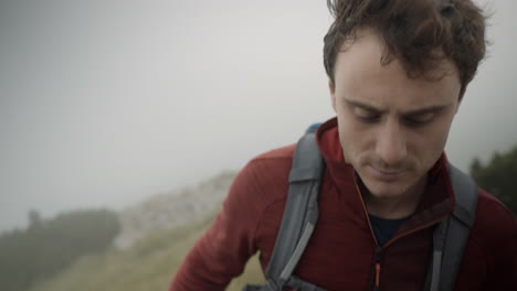 close up of a hiker in red jacket, infront, climbin up a hill of mountain stol