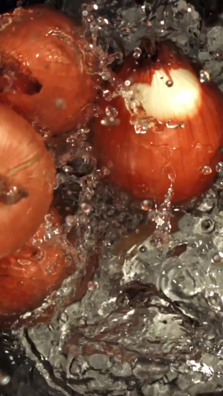 Cipolle fresche che schizzano nell'acqua in una pentola di metallo