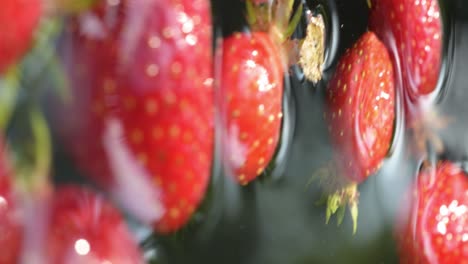 Cierre-Vertical-De-Fresa-Natural-Orgánica-En-Agua-Clara,-Fruta-Saludable