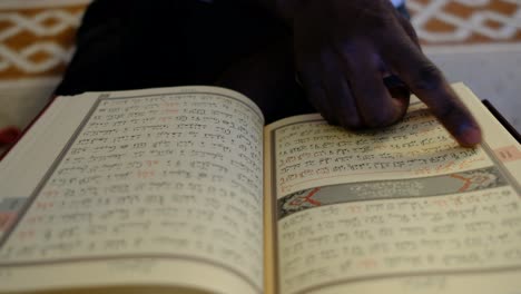 african man finger readiing quran