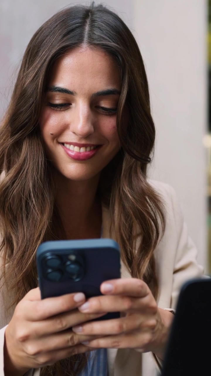 Giovane donna sorridente che usa lo smartphone in un ambiente professionale