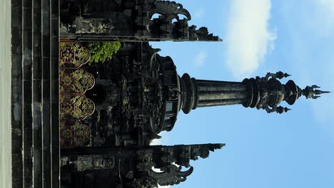 vertical slow motion shot highlighting the grandeur of the bajra sandhi monument in denpasar, bali, showcasing the intricately gilded entrance gate, colossal column, and stairway