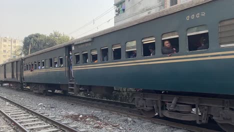 view a intercity train with a diesel locomotive carrying passengers passing through the busy city in dhaka,bangladesh on a sunny morning.
