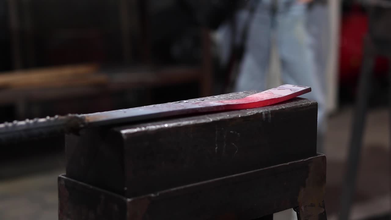 Blacksmiths forging hot metal with hammer in workshop