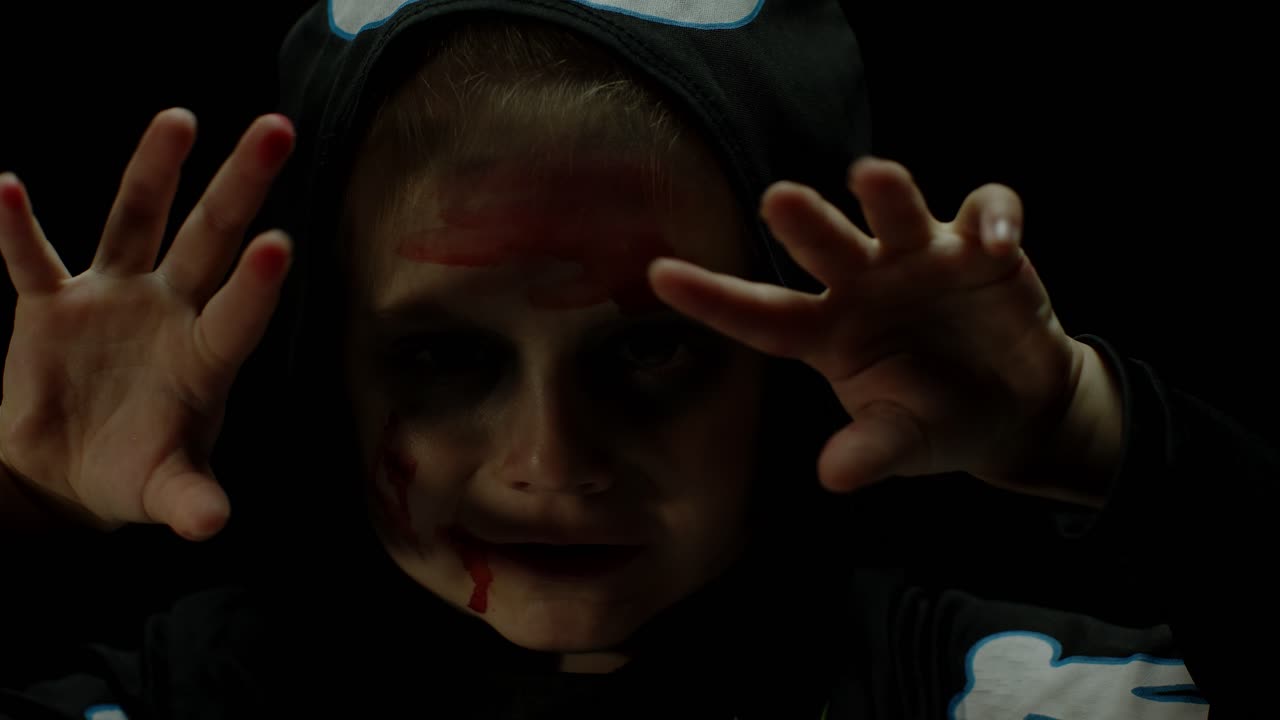 Halloween, angry girl with blood makeup on face. Kid dressed as scary skeleton, posing, making faces