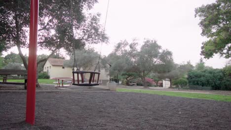 swing moves in slow motion at a playground, trees in the background, day