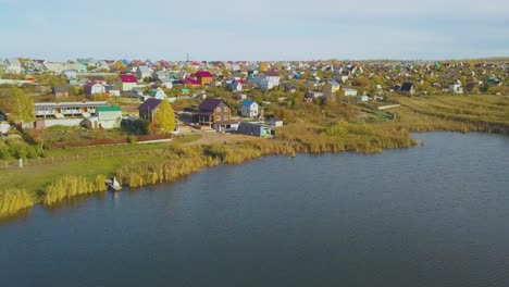 distant-couple-near-large-river-against-cottage-town-aerial