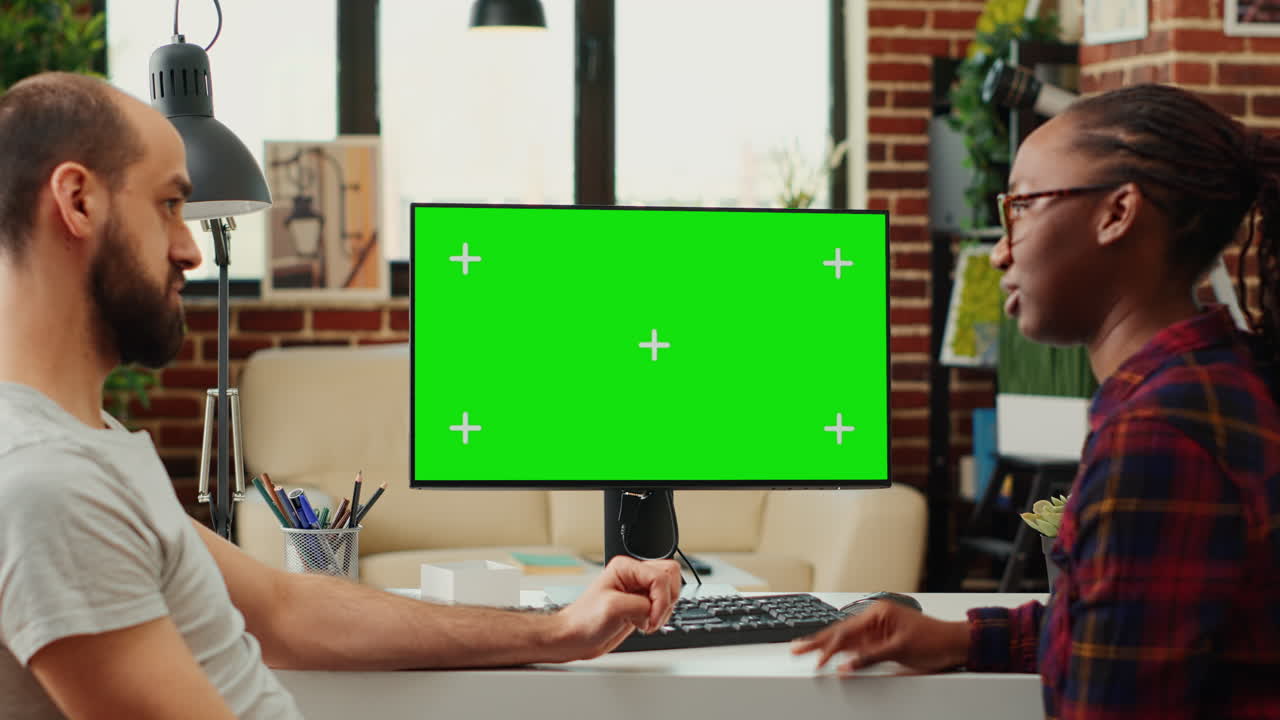 Multiethnic team of people looking at computer with greenscreen