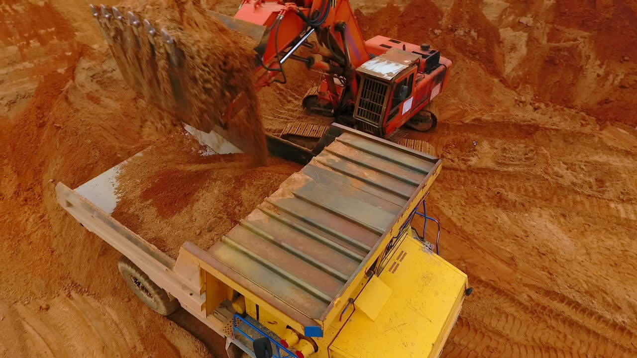 Escavatore minerario che carica sabbia su un dumper in una cava di sabbia. Benna dell'escavatore