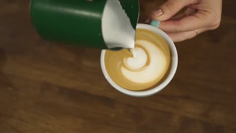 professional female barista makes tulip in cappuccino - close up