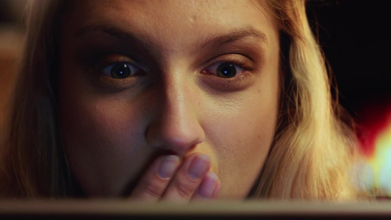 Young Woman Reacting with Surprise While Looking at a Screen