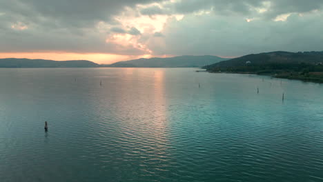 Paisaje-Tranquilo-Del-Lago-Trasimeno-Al-Amanecer-En-Umbría,-Italia---Toma-Aérea-De-Drones