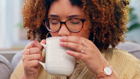 mujer negra, relajarse y tomar café en un sofá