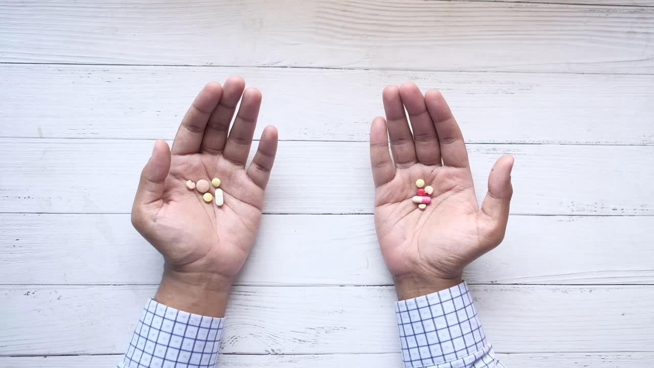 나무 테이블 에 여러 가지 종류 의 약 을 들고 있는 손 들