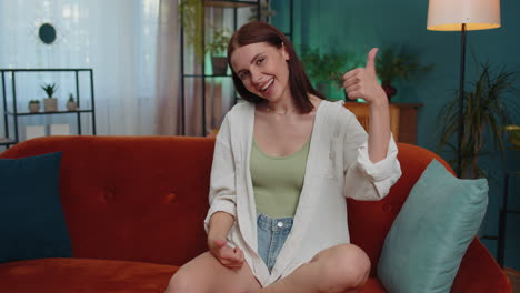 mujer joven feliz mirando con aprobación a la cámara mostrando los pulgares hacia arriba, como un signo positivo, buenas noticias