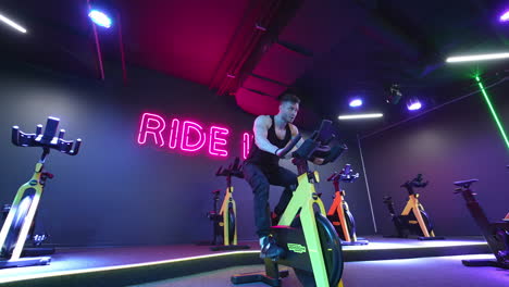 man doing cardio workout cycling bikes. footage of sportsman riding bike at the gym