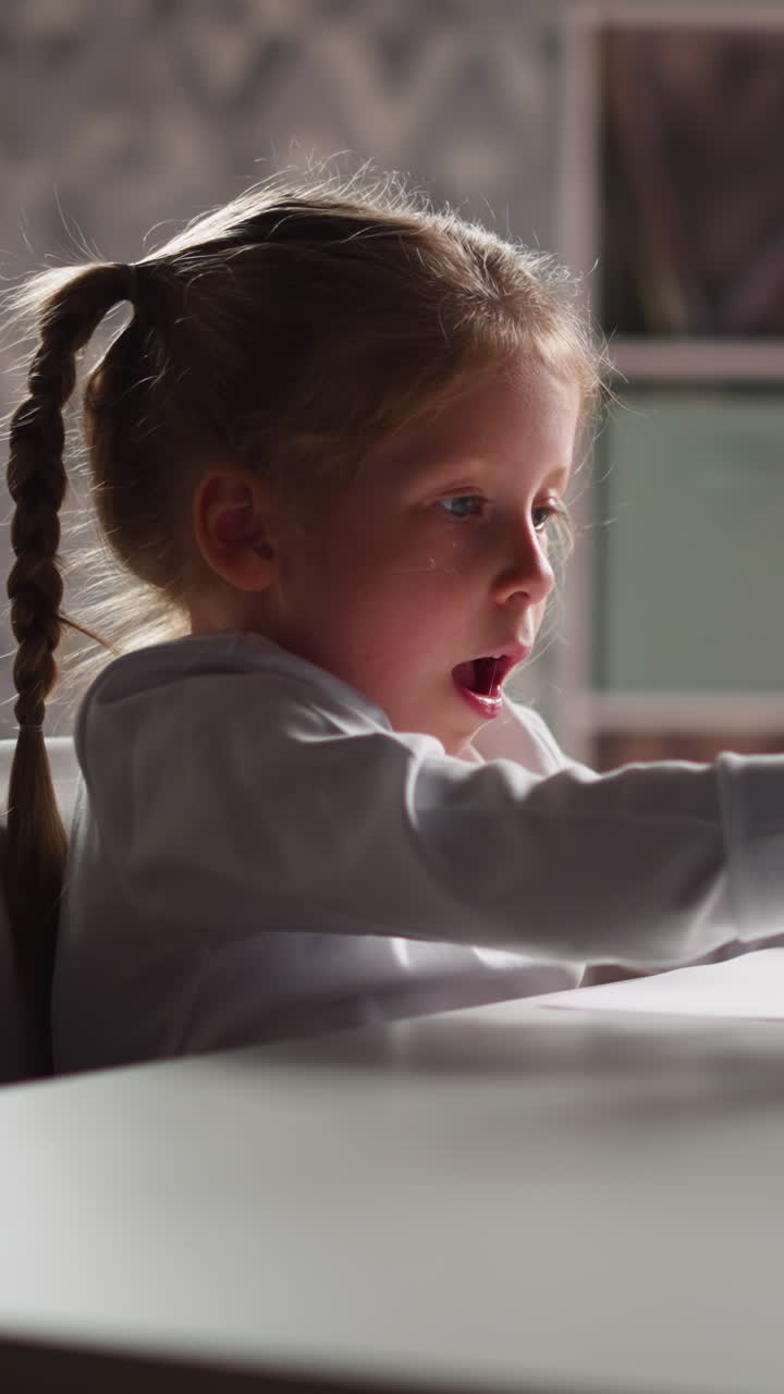 Talented little girl with braid draws abstract picture with crayons bunch sitting at table in decorated children room closeup slow motion