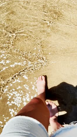 bare feet standing in sparkling shallow beach water