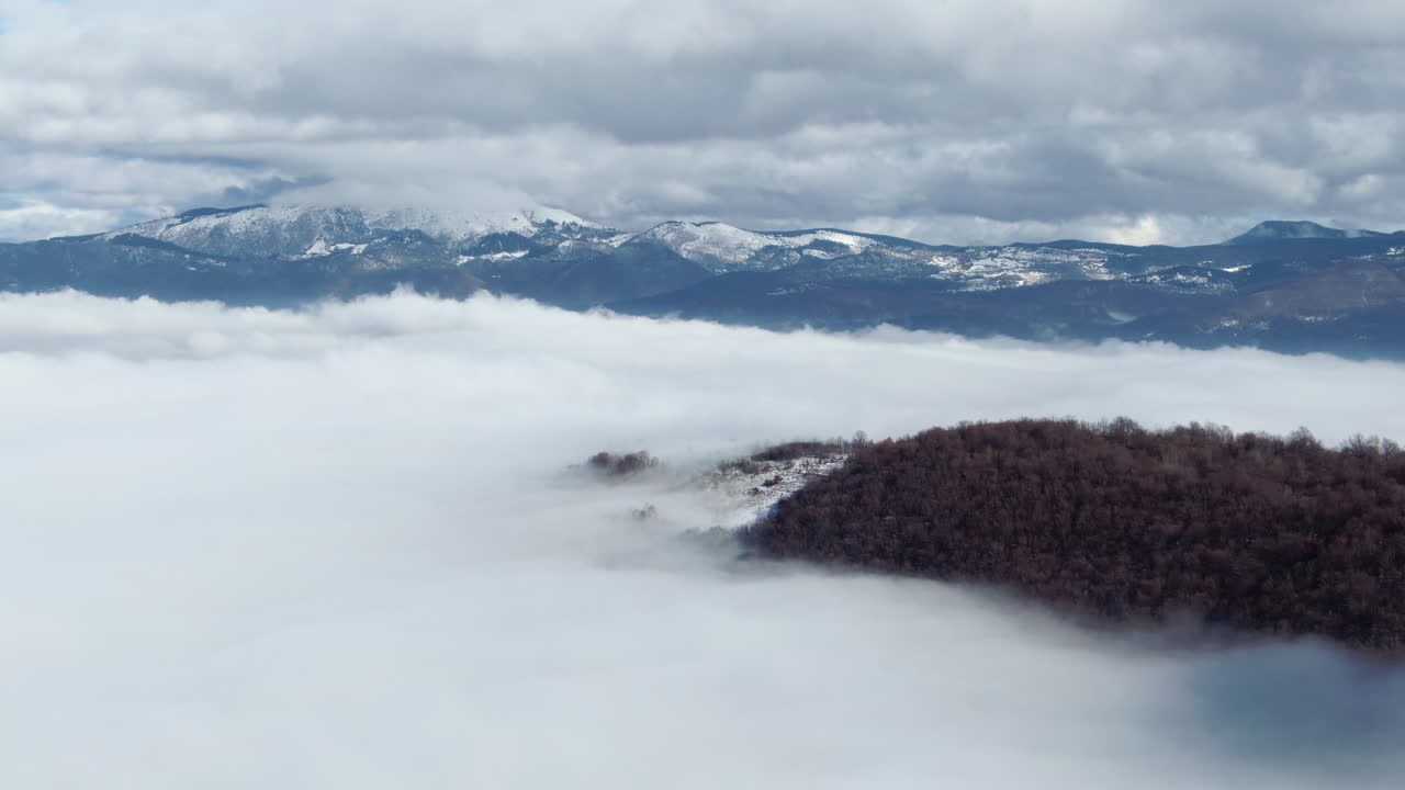 A view of mountains with clouds above the fog in the valley Trees are surrounded by a sea of white clouds Mountain peaks visible in the distance