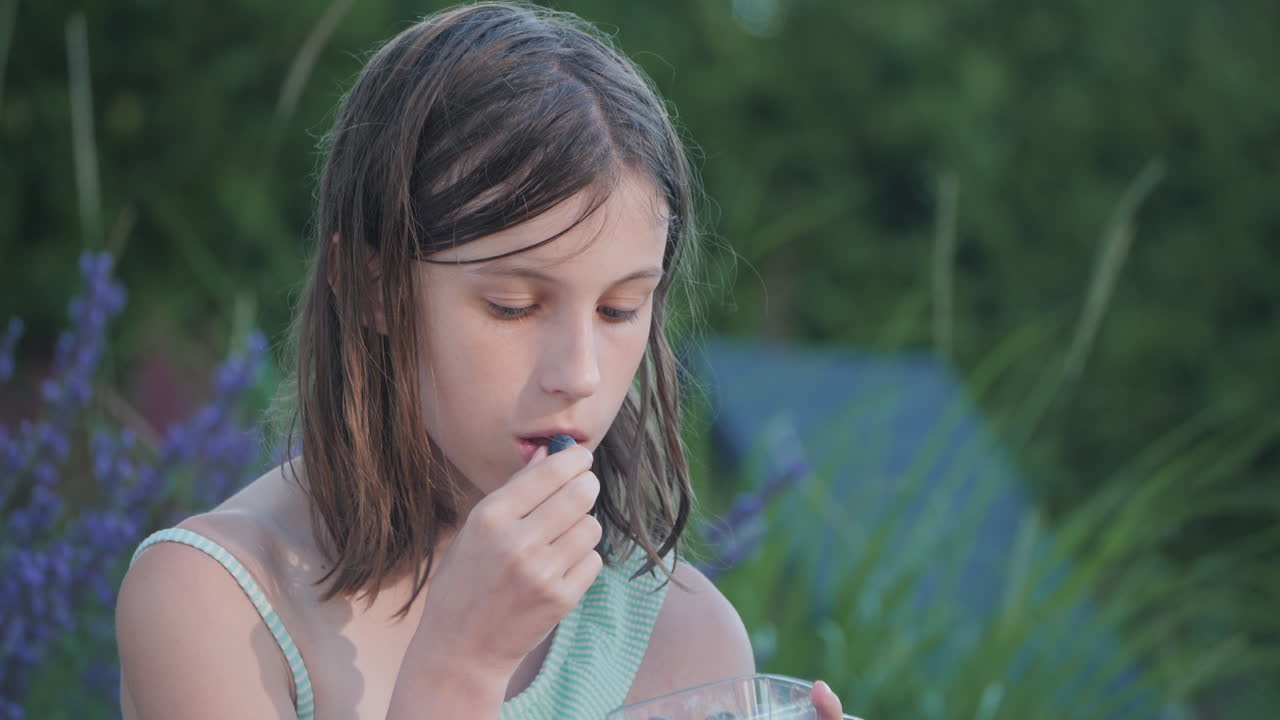 야외에서 블루베리를 먹는 소녀