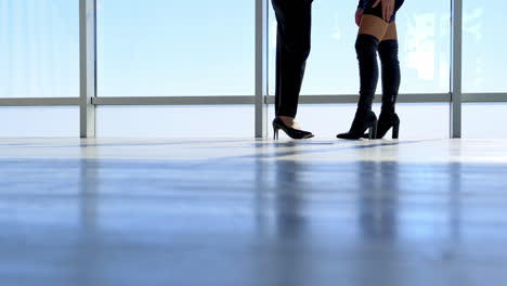legs of women meeting together. view on office floor and female's legs in high heel footwear walking on next to the windows. close-up.