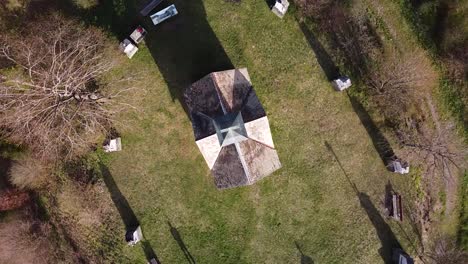 drone shot of a chapel surrounded by tombstones on top of a hill