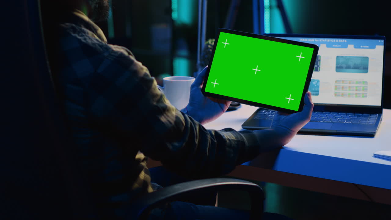 empleado remoto sosteniendo dispositivo de clave de croma, analizando gráficos de negocios