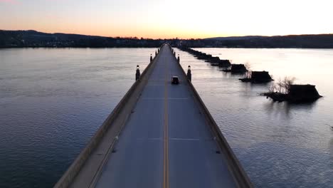 Aerial-flyover-Columbia–Wrightsville-Bridge-following-driving-cars-after-sunset-Behind-hills-at-horizon