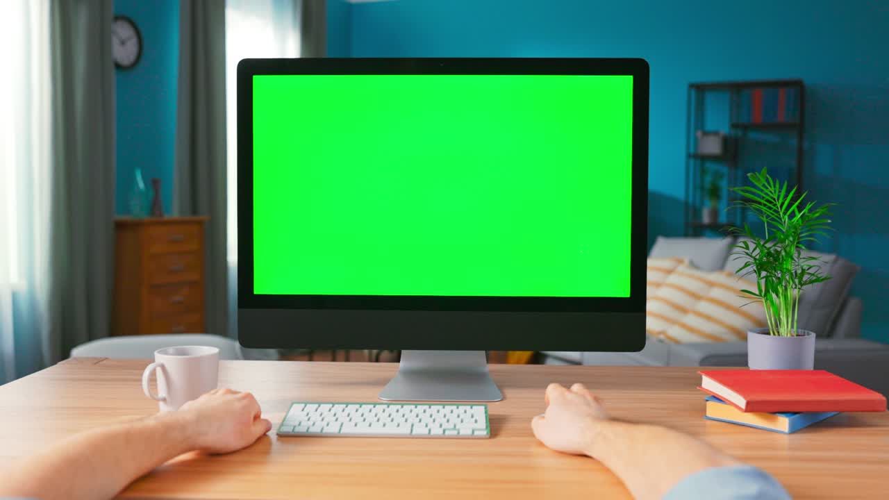 남자 손의 클로즈업은 컴퓨터 마우스를 사용합니다. 편안한 홈 오피스의 책상 위에 서있는 모형 녹색 화면 디스플레이를 가진 현대 개인 컴퓨터에 확대합니다.