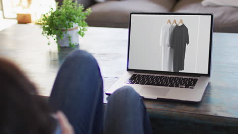 rodillas de una mujer en la mesa usando una computadora portátil, compras en línea de ropa, cámara lenta