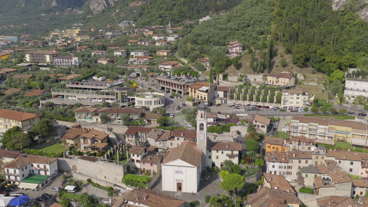 Aerial drone footage featuring a smooth forward flight toward the church in Limone sul Garda on the shores of Lake Garda. The shot captures the charming village, surrounding mountains 6k to 4K 60fps