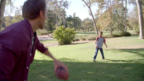 un niño de siete años jugando al fútbol con su padre en el parque.