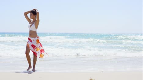 Gorgeous-young-woman-walking-along-a-beach