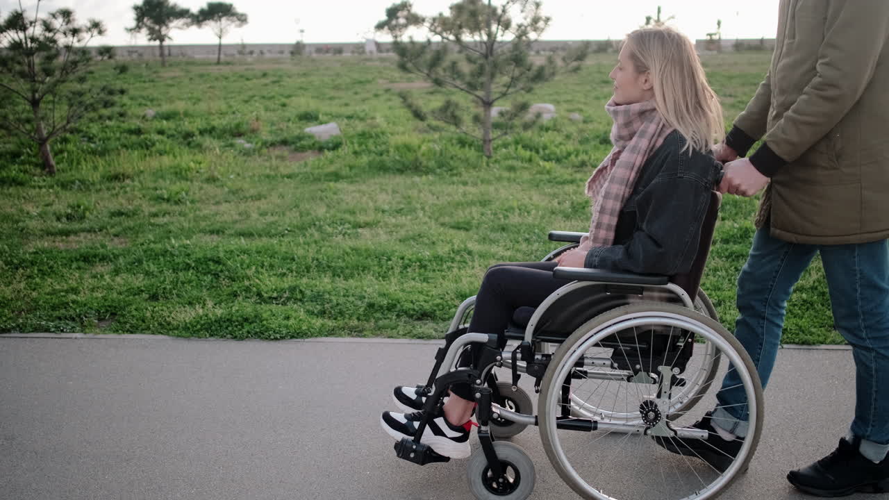 pareja apoyando a una mujer en una silla de ruedas en un parque