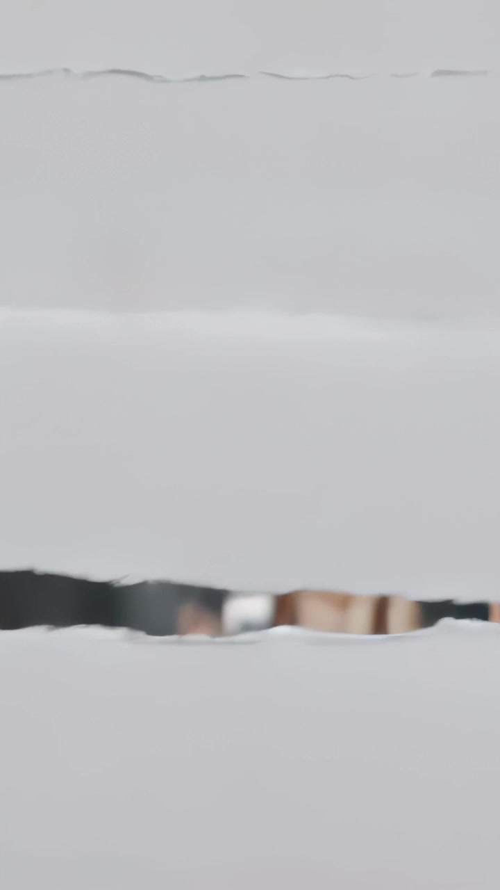Vertical video: Shifting camera revealing slatted blinds exposing torso in light top behind lights