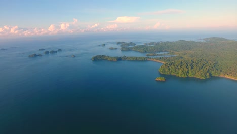 panning aerial view high above the green jungle-covered parida island at golden hour in paradise