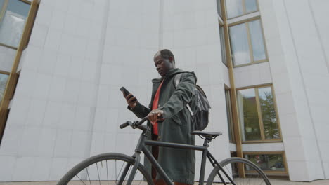 mature man with bicycle and smartphone in urban setting