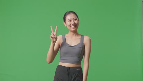 woman in activewear making peace sign