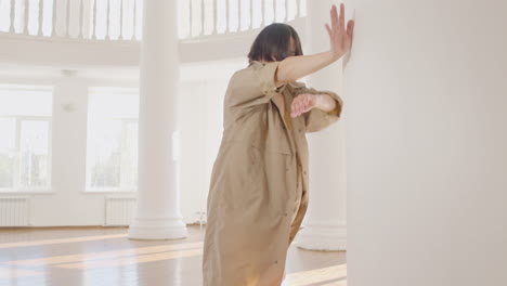 bailarín japonés masculino contemporáneo entrenando movimientos de baile apoyado en una columna en el estudio