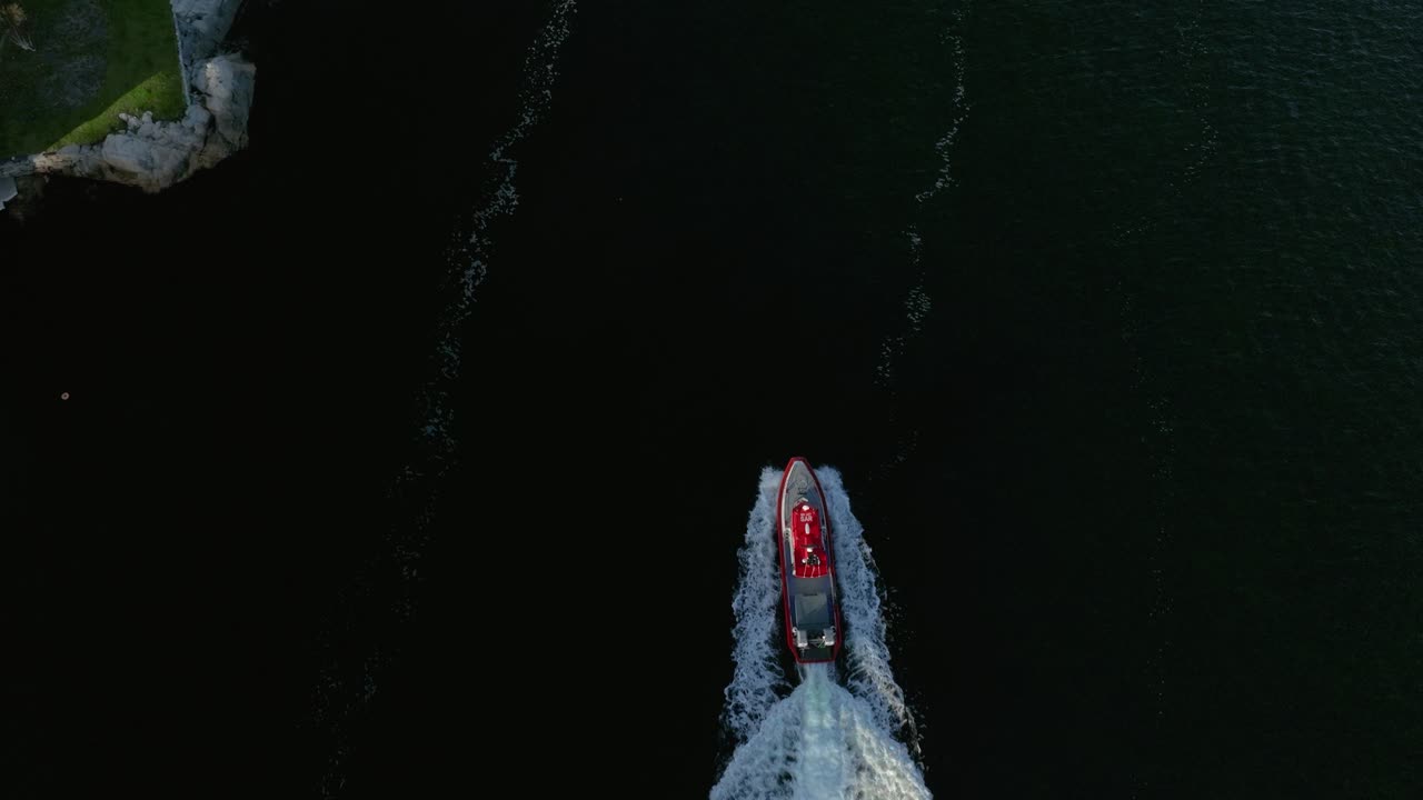 A speedboat is cruising across the ocean, leaving a white wake as it moves swiftly through the dark blue waters under a clear sky. The scene captures the thrill of the ride
